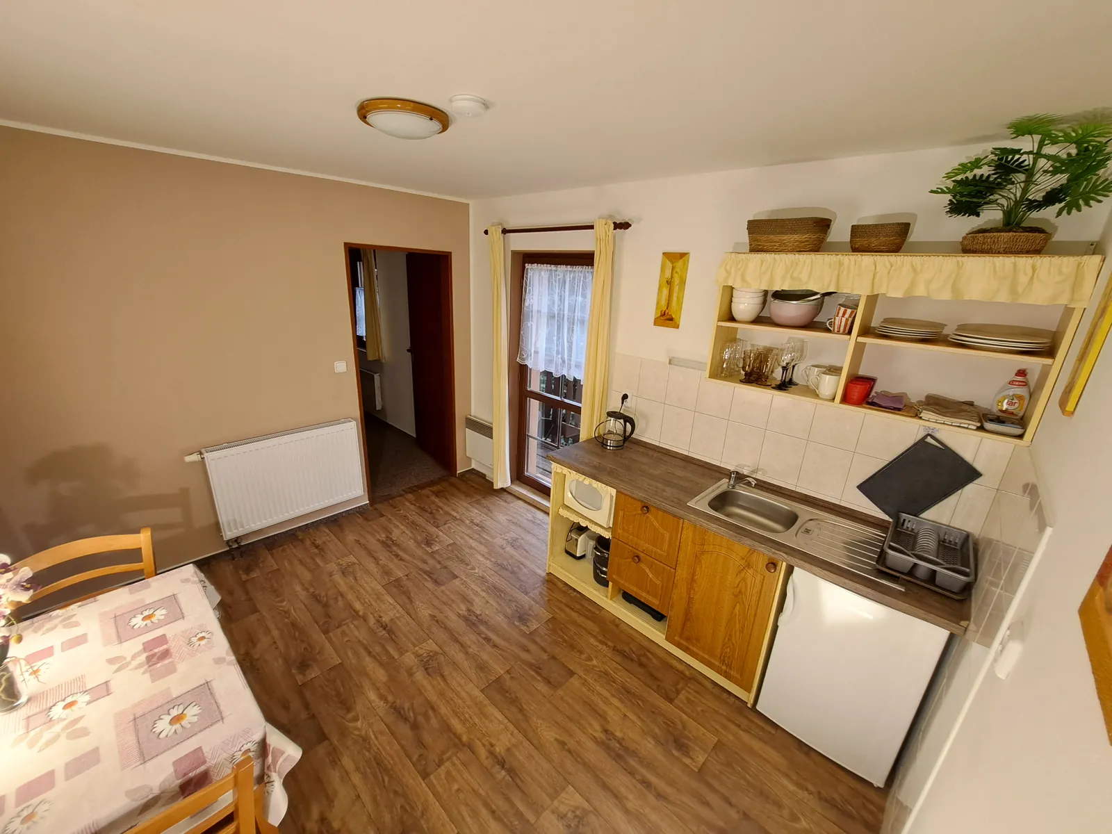 Apartmán č. 2 — kuchyňka s lednicí a mikrovlnkou, dveře na balkon