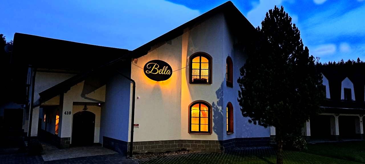 Penzion Bella večer s rozsvíceným nápisem Bella nad vchodem