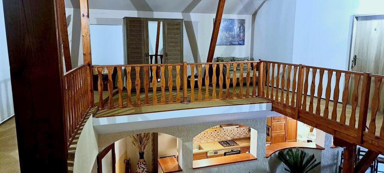 Pohled z dřevěné galerie v patře do společenské místnosti penzionu